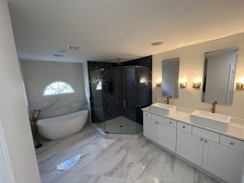 Remodeled primary bathroom with a freestanding tub and herringbone tile shower